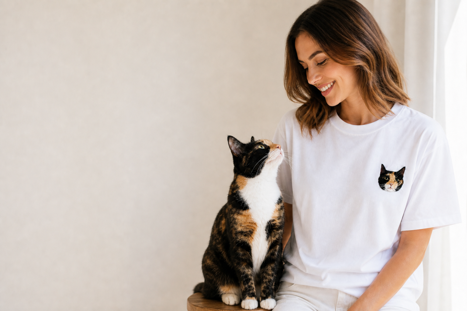 Model happily looking at matching calico cat, embroidered portrait t-shirt